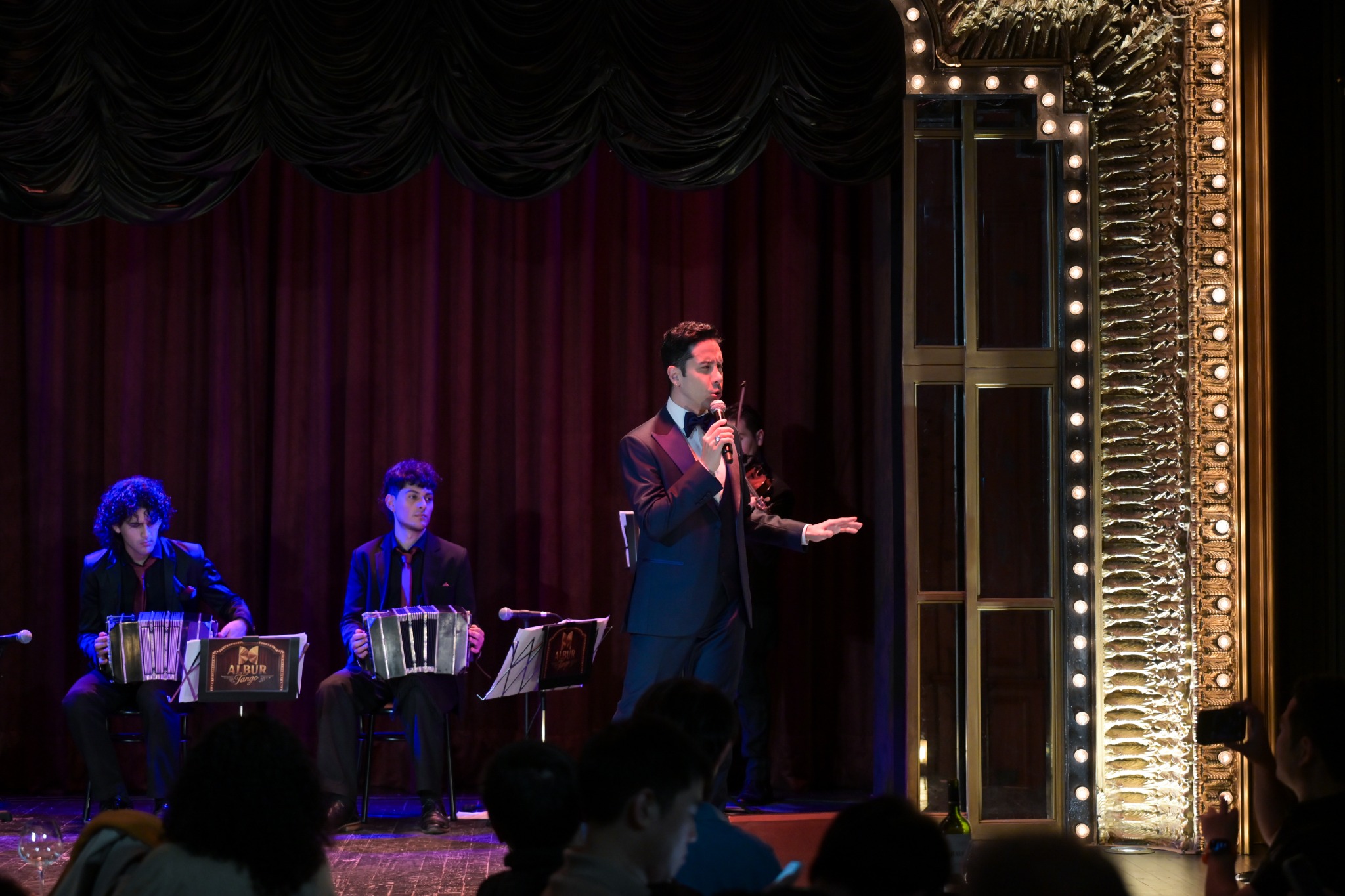 Emanuel Rivero Famá cantando junto a los bandoneonistas en el escenario de Albur Tango